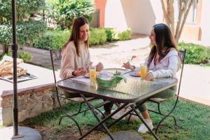 two women sitting at a table in a yard at Cachito Mio hotel y temazcal in Cholula