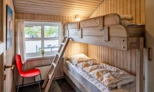 a bedroom with a bunk bed with a ladder and a chair at VE264-Vejers-Strand-Jafdalvej-95 in Vejers Strand