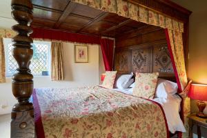 a bedroom with a canopy bed with red curtains at The Oxenham Arms Hotel Devon in South Zeal