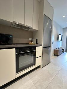 a kitchen with white cabinets and a stainless steel refrigerator at 2BR Apartment for 5 in Archangelos Rhodes with Parking - Equus Sky in Archangelos