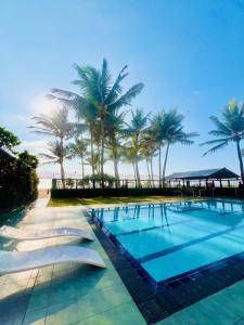 a swimming pool with palm trees on the beach at Sunset Point Beachfront Villa & Restaurant in Negombo