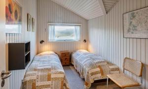 a bedroom with two beds and a tv and a window at VE465-Vejers-Strand-Violvej-1A in Vejers Strand