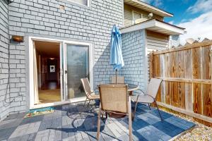a patio with a table and chairs and an umbrella at Maxs Nautical Nook Village OBX in Kitty Hawk