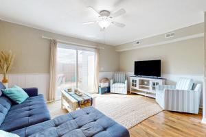a living room with a blue couch and a tv at Maxs Nautical Nook Village OBX in Kitty Hawk