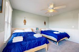 a bedroom with two beds and a ceiling fan at Maxs Nautical Nook Village OBX in Kitty Hawk