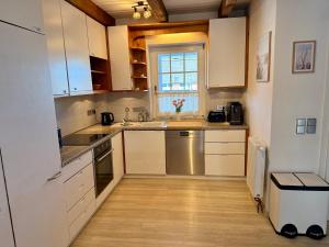 a kitchen with white cabinets and a window at Ferienhaus Schlummerkoje in Friedrichskoog