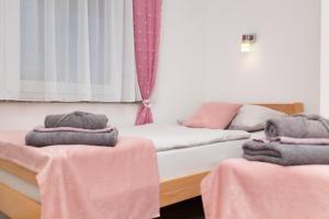 two beds in a room with pink towels on them at Apartman Orhideja in Gospić