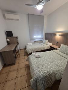 a room with three beds and a desk and a projector at Hostal De la Rosa by Parque Warner Madrid in Valdemoro