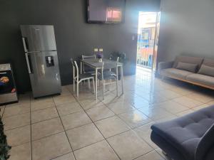 a living room with a table and a refrigerator at Quepos Explorers Hub Spacious Apartment in Quepos