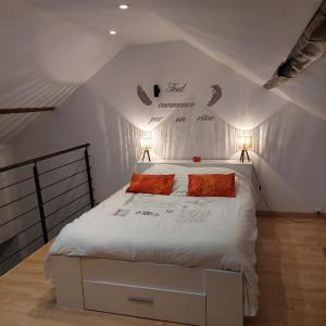 a bedroom with a white bed with two red pillows at La petite Maison in Fromelennes