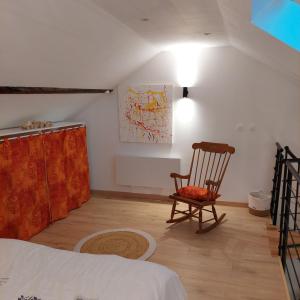 a bedroom with a chair and a painting on the wall at La petite Maison in Fromelennes