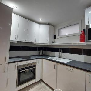 a kitchen with white cabinets and a sink at La petite Maison in Fromelennes