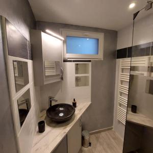 a bathroom with a sink and a window and a mirror at La petite Maison in Fromelennes