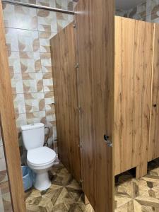 a bathroom with a toilet and a wooden door at Хостел San in Kamianske