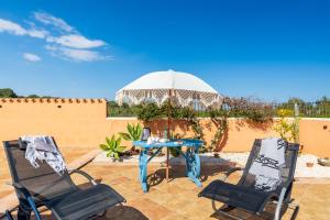a patio with two chairs and a table and an umbrella at Ri Ale Sa prassa Sardegna Ogliastra in Bari Sardo