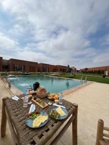 a table with food on it next to a swimming pool at Dar Fatma Charming Moroccan Guesthouse with Pool & Hammam in Sidi Bibi