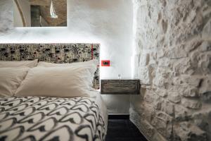 a bedroom with a bed and a stone wall at Vico Santa Maria in Putignano
