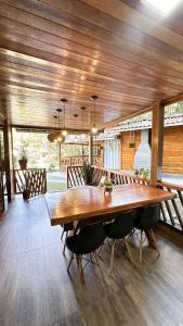 a dining room with a large wooden table and chairs at Chale Allegra - Hidro Aquecida - Vista para o Lago in Venda Nova do Imigrante