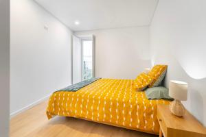 a bedroom with a bed with a yellow comforter at Leiria Boutique Apartment in Leiria