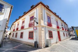 a white building with red windows on a street at Leiria Boutique Apartment in Leiria
