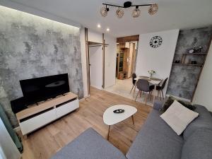 a living room with a couch and a tv and a table at Apartament TARNÓW LWOWSKA CENTRUM in Tarnów