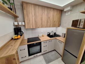 a small kitchen with wooden cabinets and a stove top oven at Apartament TARNÓW LWOWSKA CENTRUM in Tarnów