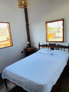a bedroom with a large white bed with two windows at Mi bohío in Monteverde