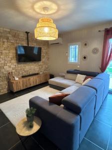 a living room with a blue couch and a tv at La Villa Carpentrassien in Carpentras