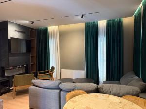 a living room with green curtains and a couch at Vila 76 Belvedere in Korçë