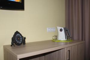 クラスノダールにあるHotel Vegaのコーヒーメーカー付きカウンターと時計