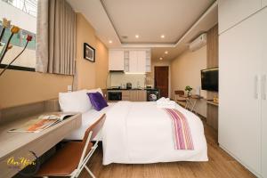 a bedroom with a large white bed and a kitchen at An Yên Island - Art Boutique Stay with Dual Lake view in Hanoi
