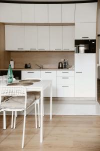a kitchen with white cabinets and a white table and chairs at Apartmány park in Poděbrady