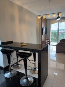 a kitchen with a black island with bar stools at Apartamento completo no Planalto in Belo Horizonte