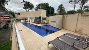a swimming pool with two benches next to a building at Apartamento completo no Planalto in Belo Horizonte