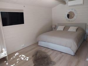 a bedroom with a bed and a flat screen tv at Chalet cosy avec terrasse & hamac, calme, proche plage, parking, NC Properties in Grimaud