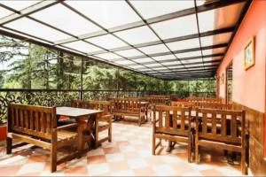 a restaurant with wooden benches and a table and a balcony at Hotel Sandhya in Kasol