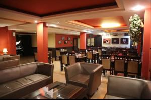 a restaurant with couches and tables and a bar at Hotel Sandhya in Kasol