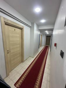 a hallway with a wooden door and a red carpet at Marin konaklama in Pendik