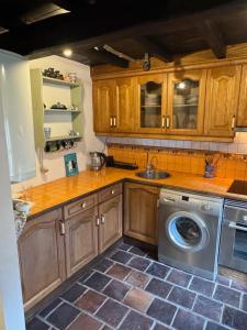 a kitchen with wooden cabinets and a washing machine at Casa de Aldea EL Fusu in Taranes