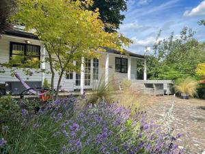 a white house with a garden with purple flowers at Sailaway Holiday Cottage in Norwich