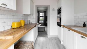 a kitchen with white cabinets and a wooden counter top at The Stay at Straad in Island of Bute