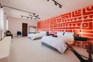 a bedroom with two beds and a red wall at Cocoon Oaxaca City- Curated Stay In Oaxaca Centro in Oaxaca City