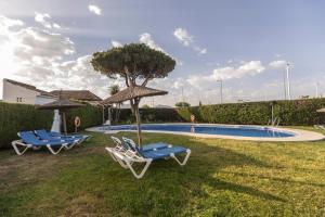 a group of chairs and umbrellas next to a swimming pool at BLUESEA El Cortijo in Matalascañas