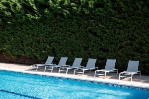 eine Reihe von Liegestühlen neben einem Schwimmbecken in der Unterkunft BLUESEA Noja in Noja