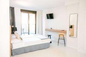 a white bedroom with a bed and a mirror at BLUESEA Faro Cullera in Cullera +2 photos
