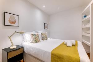 a white bedroom with a bed and a lamp on a night stand at Bairro Alto Cozy apartment in Lisbon