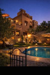 a house with a swimming pool in front of a building at Riad Des Vieilles Charrues in Boumalne Dades