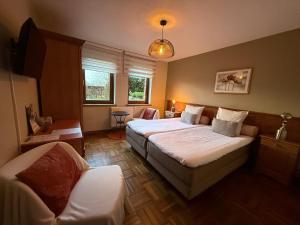 a bedroom with two beds and a chair in it at A la ferme du Pere Eugene in Malmedy