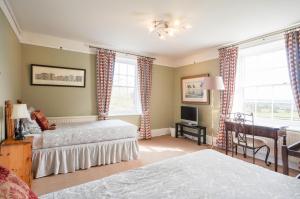 a bedroom with two beds and a desk at Colthrop Manor B&B in Thatcham