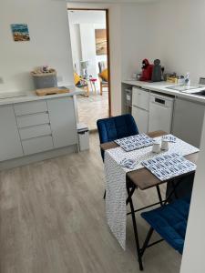a kitchen with a table and blue chairs and a kitchen with white cabinets at East Barn Garden View in Georgeham